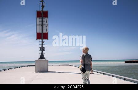 Frau, die auf dem Pier herumschlendert und den Lake Huron betrachtet. Stockfoto