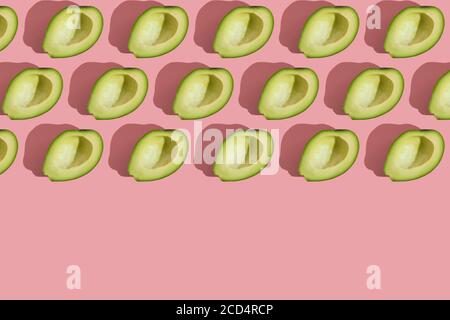 Trending Stil Muster der Hälfte seedless grün Avocado auf rosa Hintergrund mit hartem Licht. Kreative Lebensmitteltextur Stockfoto