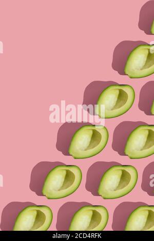 Trending Stil Muster der Hälfte seedless grün Avocado auf rosa Hintergrund mit hartem Licht. Kreative Lebensmitteltextur Stockfoto