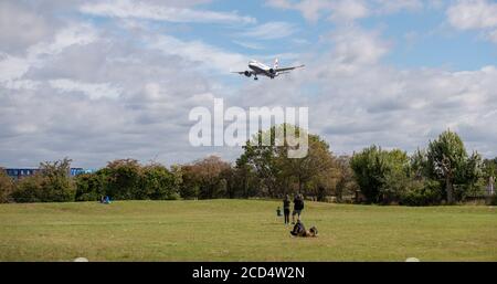 Flughafen Heathrow, London, Großbritannien. 26. August 2020. British Airways Airbus A320 G-TTNF über Bäumen auf der Landebahn 27L in Heathrow bei Windböen, beobachtet von Planespottern auf einem grünen Feld. COVID-19 Pandemie hat die Luftfahrtindustrie weltweit einbruch, mit rund 11% der Passagiere in Heathrow im Juli 2020 im Vergleich zum gleichen Monat im Jahr 2019, und rund 25% der Flugbewegungen in Heathrow im Juli 2020 im Vergleich zum Juli 2019. Kredit: Malcolm Park/Alamy. Stockfoto