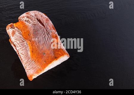 Gefrorene rohe Schweinehals Koteletts Fleischsteak auf Schiefer isoliert. Gefrorene, ungekochte Scheiben Rindersteaks, Filet oder Rippenauge mit Eiskristallen darauf. Stockfoto