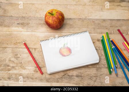 Kinderzeichnung, Apfel und Buntstifte. Holztisch. Draufsicht Stockfoto