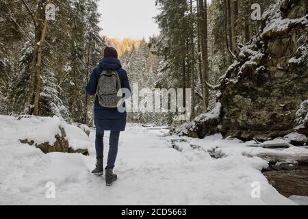 Mädchen mit Rucksack steht in einem verschneiten Wald. Wintertag. Stockfoto