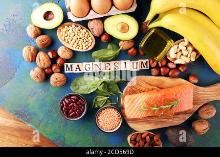 Magnesiumhaltige Produkte: Bananen, Mandeln, Avocado, Nüsse und Spinat und Eier auf dem Tisch Stockfoto