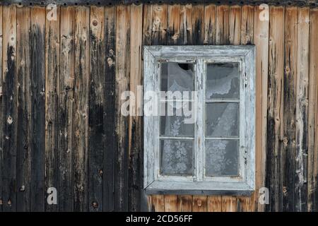 Vintage Holzfenster in einer Wand aus schäbigen dunklen Holzbrettern mit Knoten. Frontalansicht. Nahaufnahme Stockfoto
