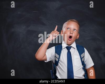 Emotional überrascht kaukasischen Schuljunge in Hemd und Krawatte zeigen Finger nach oben und Öffnung Mund weit, schockiert mit erstaunlichen unerwarteten Nachrichten Stockfoto