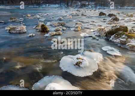 Platten von Eiskristallen auf Felsen im fließenden Fluss Isar In der Nähe von München an kalten nebligen Wintertag Stockfoto