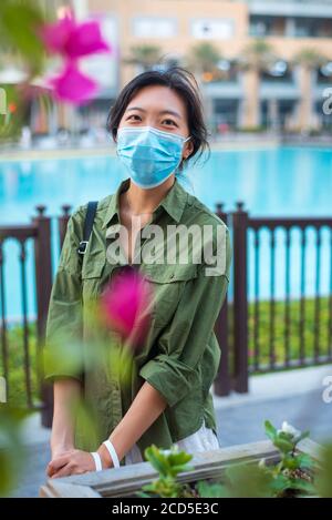 Asiatische Frau trägt chirurgische Gesichtsmaske im Außenbereich eines Einkaufszentrums in Dubai. Reisen und Freizeit neue Normalität nach Coronavirus Covid-19 Pandemie Stockfoto