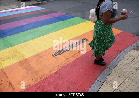 Fußgänger gehen am 24. August 2020 in Birmingham, Großbritannien, über eine regenbogenfarbene Kreuzung. Die mehrfarbige Kreuzung wurde im Design der Regenbogenfahne geschaffen, die in der ganzen Welt als Symbol zur Feier der LGBTQ-Gemeinschaft angenommen wurde. Stockfoto