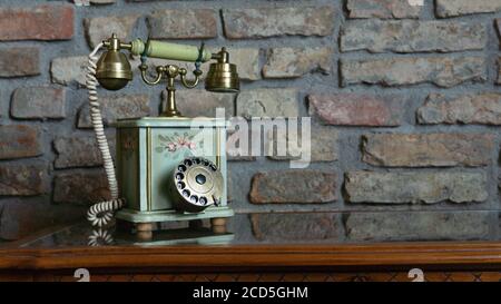 Elegantes Vintage altes Telefon auf elegantem Holztisch gegen Backstein Wandentspannung antike Innenausstattung Vintage Dekoration Stockfoto