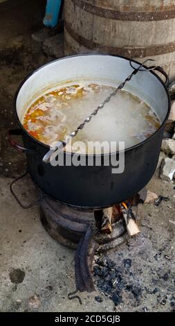 Land Holz brennenden großen gusseisernen Topf. Outdoor Pottage Kochen traditionelle Küche Fleischbällchen Suppe Stockfoto