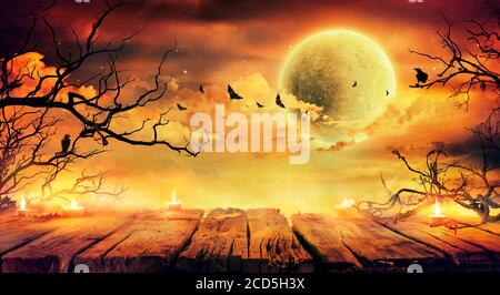 Halloween In Orange - Alter Tisch Mit Kerzen Und Ästen Bei Unheimliche Nacht Mit Vollmond Stockfoto