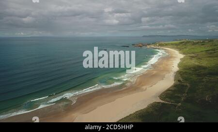 Luftaufnahme Sandstrand: ozean schäumende Wellen fällt an die Küste in White Beach, Antrim County. Küste der malerischen Natur von Nordirland. Dramatische Sommerlandschaft am Tag Stockfoto