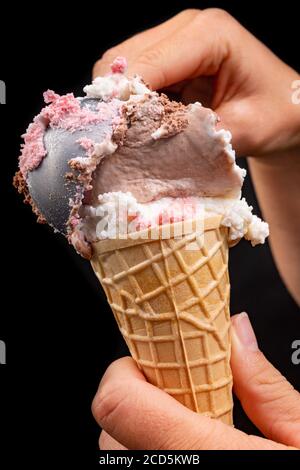Leckere Eiscreme mit einem Eislöffel auffüllen. Fruchtdessert in einer knusprigen Wafer. Schwarzer Hintergrund. Stockfoto