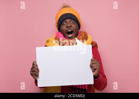 Überrascht junger afroamerikanischer Mann hält Plakat überrascht mit nachrichten Stockfoto