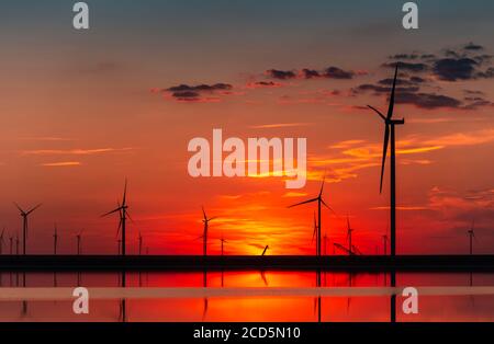 Windpark bei Sonnenuntergang; Windturbinen am brennenden Himmel; Hintergrund des Windparks Stockfoto