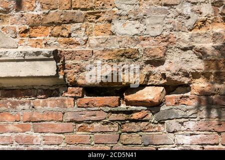 Baufällig mit Schlaglöchern alte Backsteinmauer des Gebäudes, aus rotem Backstein, aus nächster Nähe. Hintergrund oder Textur. Stockfoto