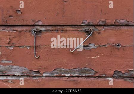 Metall-Rollladenhaken hängen an alten hölzernen braun bemalten Wand. Holzstruktur Hintergrund, braune Holzbretter. Stockfoto