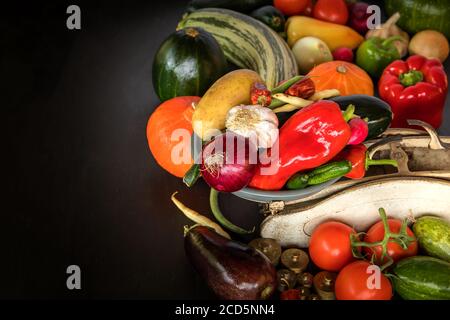 Frisches Gemüse und alte Küchenwaage auf schwarzem Hintergrund. Ernte von Gemüse. Gesunde Ernährung. Stockfoto