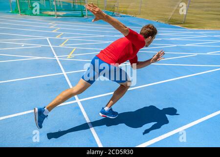 Laufsportler beginnt mit dem Laufen zu Beginn der Laufstrecke auf blauen Laufstrecken in der Leichtathletik und im Feldstadion. Sprinter im Rennen. Sport und Stockfoto