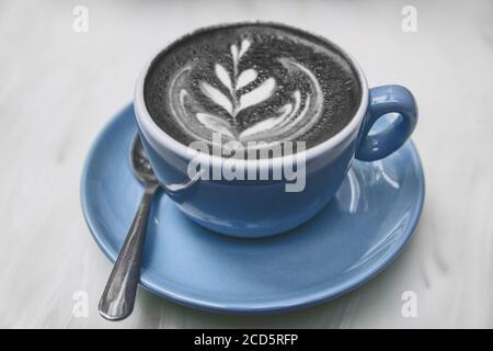 Charcoal Latte Kaffeetasse Aktivkohle schwarzes Pulver gemischt Cappuccino Milchschaum für gesunde Entgiftung Kater Heilung amerikanischen Trend Stockfoto