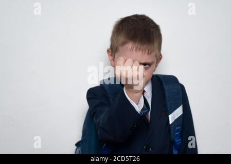 Schuljunge droht mit seiner Faust. Junge in Schuluniform. Weißer Hintergrund. Brawler Stockfoto