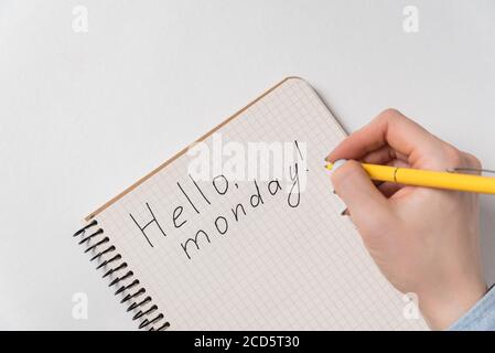 Motivationsnotice im Notepad Hallo Montag. Guter Start in die Woche. Weibliche Hand schreibt Stockfoto