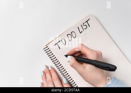 To-Do-Liste. Weibliche Hände schreiben in Notepad. Liste der Pläne für Tag, Planung. Weißer Hintergrund Draufsicht. Stockfoto