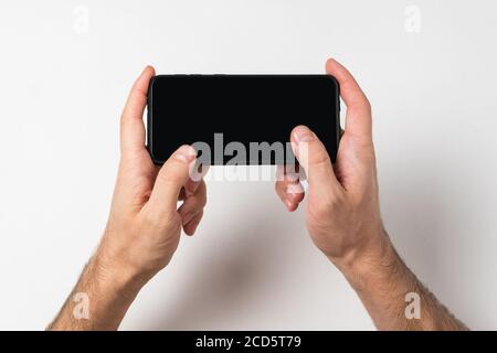 Männliche Hände halten Smartphone auf weißem Hintergrund. Leerer Bildschirm. Speicherplatz kopieren. Stockfoto