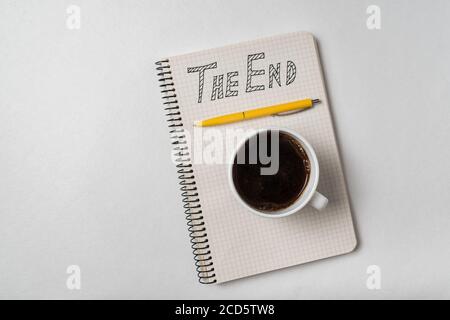 Copybook mit dem Endtext. Notizblock, Stift und Tasse Kaffee auf weißem Hintergrund. Stockfoto