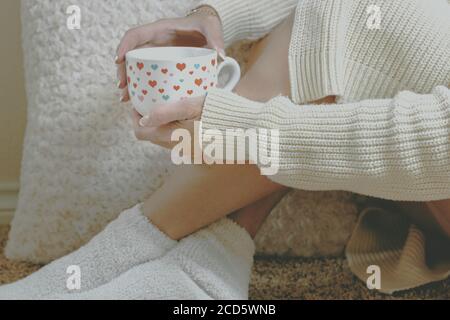 Gemütlich zu Hause mit warmen Socken und einem heißen Tee In einem Becher Stockfoto