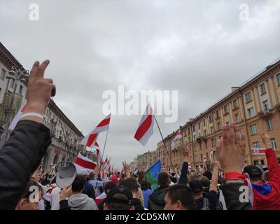 Minsk / Weißrussland - 23 2020. August: Demonstranten mit weiß-rot-weißen Fahnen heben Hand in das Siegeszeichen, während sie durch die Innenstadt marschieren Stockfoto