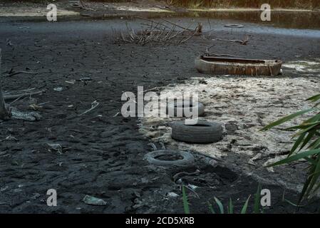 Müll und alte Reifen am Flussufer. Umweltverschmutzung. Ökologie-Konzept. Stockfoto