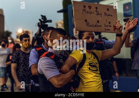 Barcelona, Spanien. August 2020. Sicherheitskräfte begleiten einen Fan des FC Barcelona, der ein Schild mit der Aufschrift "Messi stay Home - Barcelona - I love you" trägt, während eines Protestes um den Verbleib von Fußballstar Messi im Club. Bereits in der Nacht zuvor waren mehrere Fans des Clubs vor Camp Nou gezogen und forderten den Rücktritt von Clubpräsident Bartomeu. Quelle: Matthias Oesterle/dpa/Alamy Live News Stockfoto