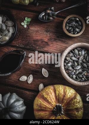 Trockene Hortensien, Kürbisse, Kürbisöl und Samen in Holzschüsseln auf Vintage-Holztisch. Herbstkonzept. Overhead-Aufnahme. Stockfoto