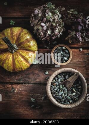 Trockene Hortensien, Kürbisse, Kürbisöl und Samen in Holzschüsseln auf Vintage-Holztisch. Herbstkonzept. Overhead-Aufnahme. Stockfoto