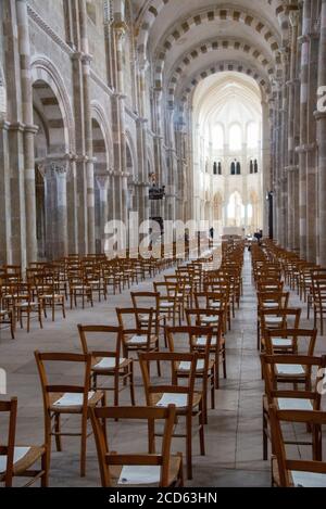 Interieur mit vielen Stühlen und Schildern für Abstand halten wegen covid-19 in der Basilika St. Marie Madeleine in Vezelay in Frankreich Stockfoto