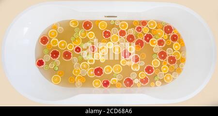 Blick von oben auf die mit Wasser gefüllte Badewanne, gemischte Scheiben von frischen Zitrusfrüchten. Stockfoto