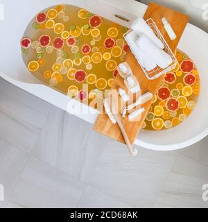 Badewanne mit gemischten Scheiben von frischen Zitrusfrüchten und Spa-Set aus Naturprodukten. Stockfoto