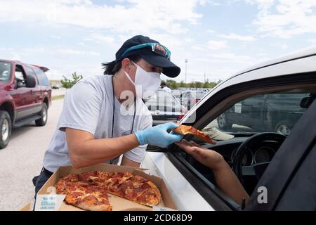 Austin, TX USA 26. August 2020: Die Feuerwehrleute von Austin und Travis County bieten Fahrern von Hunderten von Autos aus dem Küstengebiet im Osten von Texas und im Südwesten von Louisiana kostenlose Pizza an, während sie in einer Schlange in einem Hurricane Laura Evakuierungszentrum in Austin warten. Fahrer, die früh ankommen, erhalten Gutscheine für Hotelzimmer. Sobald diese ausgelaufen waren, wurden die Fahrer zu anderen Evakuierungszentren in Waco und Dallas geleitet. Laura wird voraussichtlich über Nacht als Sturm der Kategorie 4 landen und verheerende Schäden an der Küste von Texas und Louisiana und im Landesinneren anrichten. Kredit: Bob Daemmrich/Alamy Live Nachrichten Stockfoto