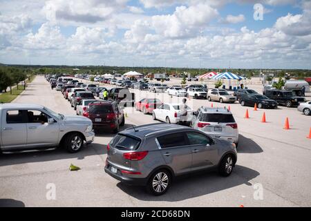 Austin, TX USA 26. August 2020: Hunderte von Autos aus dem Küstengebiet von Ost-Texas und dem Südwesten Louisianas warten in der Schlange vor einem Hurricane Laura Evakuierungszentrum, das von Austin-Beamten auf den Parkplätzen der Rennstrecke Circuit of the Americas eingerichtet wurde. Fahrer, die früh ankommen, erhalten Gutscheine für Hotelzimmer. Sobald diese ausgelaufen waren, wurden die Fahrer zu anderen Evakuierungszentren in Waco und Dallas geleitet. Laura wird voraussichtlich über Nacht als Sturm der Kategorie 4 landen und verheerende Schäden an der Küste von Texas und Louisiana und im Landesinneren anrichten. Kredit: Bob Daemmrich/Alamy Live Nachrichten Stockfoto