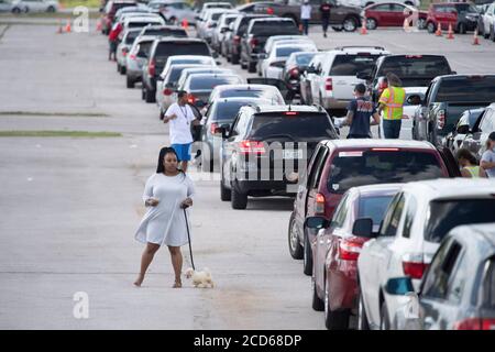 Austin, TX USA 26. August 2020: Hunderte von Autos aus der Küste von Ost-Texas und dem Südwesten Louisianas warten in der Schlange an einem Hurricane Laura Evakuierungszentrum auf dem Circuit of the Americas Rennbahn Parkplatz. Nachdem sie Stunden in ihrem Auto verbracht hat, geht diese Frau zu ihrem Hund. Fahrer, die früh ankommen, erhalten Gutscheine für Hotelzimmer. Sobald diese ausgelaufen waren, wurden die Fahrer zu anderen Evakuierungszentren in Waco und Dallas geleitet. Laura wird voraussichtlich über Nacht als Sturm der Kategorie 4 landen und verheerende Schäden an der Küste von Texas und Louisiana und im Landesinneren anrichten. Kredit: Bob Daemmrich/Alamy Live Nachrichten Stockfoto