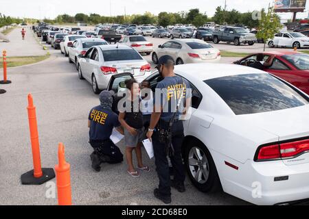 Austin, TX USA 26. August 2020: Hunderte von Autos aus dem Osten von Texas und dem Südwesten von Louisiana warten in der Schlange an einem Hurricane Laura Evakuierungszentrum auf der Rennstrecke Circuit of the Americas. Nach Stunden im Auto, bekommt diese Familie etwas frische Luft und Informationen von Austin Feuerwehrleute, die das Zentrum besetzt. Laura wird voraussichtlich über Nacht als Sturm der Kategorie 4 landen und verheerende Schäden an der Küste von Texas und Louisiana und im Landesinneren anrichten. Kredit: Bob Daemmrich/Alamy Live Nachrichten Stockfoto