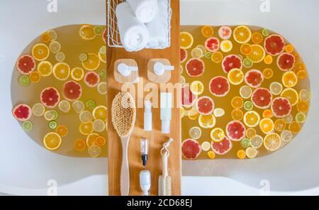 Badewanne mit gemischten Scheiben von frischen Zitrusfrüchten und Spa-Set aus Naturprodukten. Stockfoto