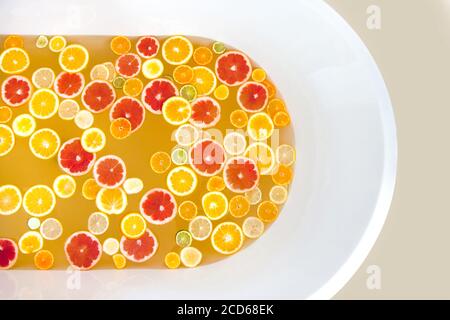 Blick von oben auf die mit Wasser gefüllte Badewanne, gemischte Scheiben von frischen Zitrusfrüchten. Stockfoto