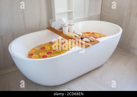 Badewanne Füllung mit Wasser, gemischte Scheiben von frischen Zitrusfrüchten und Spa-Set von Naturprodukten. Stockfoto