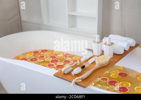 Badewanne Füllung mit Wasser, gemischte Scheiben von frischen Zitrusfrüchten und Spa-Set von Naturprodukten. Stockfoto