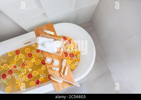 Badewanne mit gemischten Scheiben von frischen Zitrusfrüchten und Spa-Set aus Naturprodukten. Stockfoto