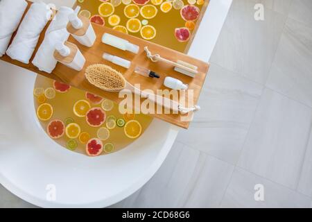 Badewanne mit gemischten Scheiben von frischen Zitrusfrüchten und Spa-Set aus Naturprodukten. Stockfoto