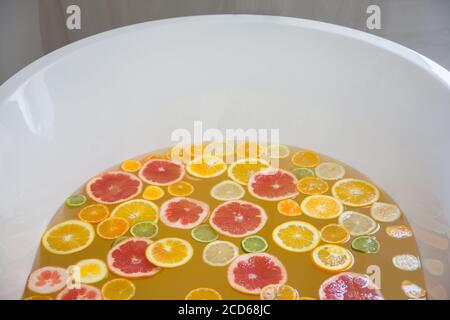 Badewanne Füllung mit Wasser, gemischte Scheiben von frischen Zitrusfrüchten. Stockfoto